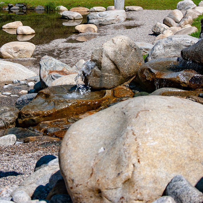 Naturbad Sirnitz — natural pond with stone surroundings and mountain view